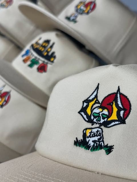 Cream caps embroidered with colorful tattoo-inspired designs