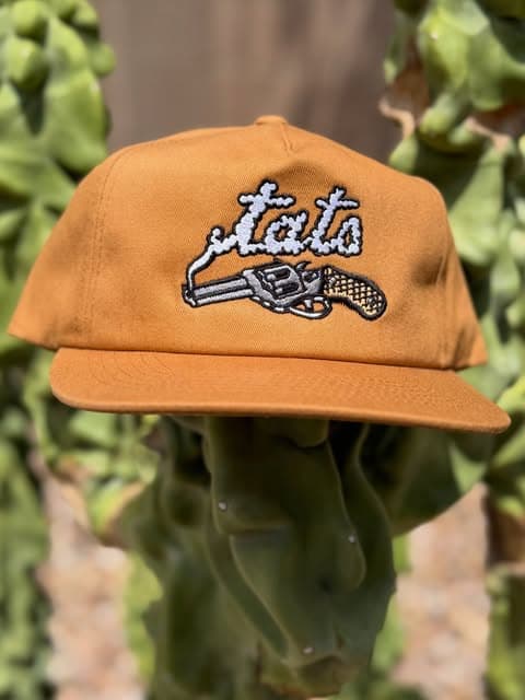A rust-colored cap embroidered with a white revolver and Jets lettering